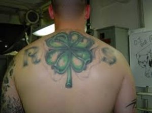 A four leaf clover tattoo on the back, with R and S on the left and right, respectively. An X seems imposed on the clover.