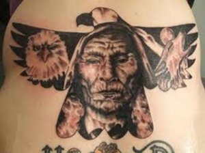 A tattoo of the face of Lakota Indian Red Cloud with an eagle headdress. The eagles wings are spread and the image of another eagle's head is on one wing and an image of a wolf's head is on the other wing.