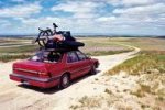 This is an image of a car full of people with their things on the top of the car going on a road trip.