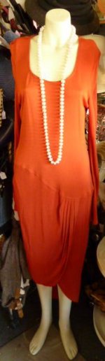 This is an image of a 1930s burnt orange evening dress, with a set of pearls.