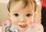 This is an image of a baby eating, with food all over her face