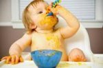 This is an image of a baby feeding themselves food